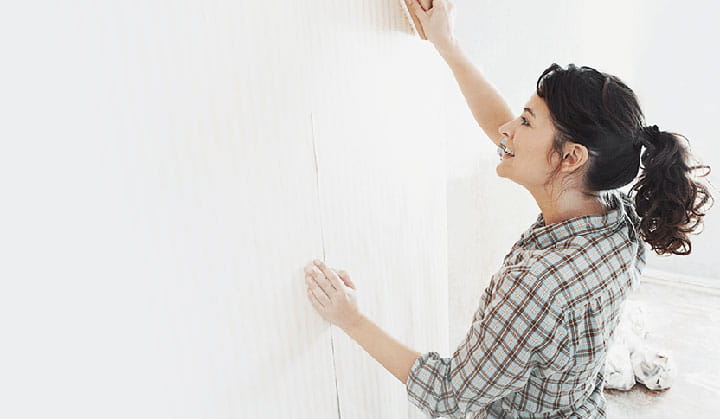 Person putting up new wallpaper with new funding through BOK HELOC loan. 